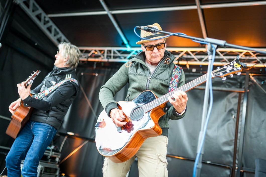 Auf dem Foto sind zwei Männer, die Gitarren spielen, auf einer Bühne zu sehen.