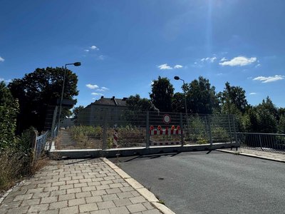 Auf dem Bild ist eine bewachsene Brücke mit Absperrung zu sehen.