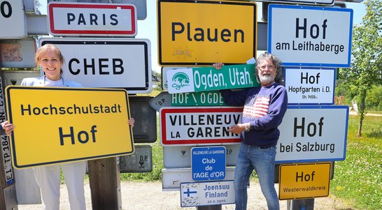 Auf dem Bild sind eine Frau und ein Mann zu sehen, die Schilder hochhalten.