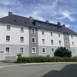 Auf dem Bild ist ein graues Mehrfamilienhaus zu sehen.