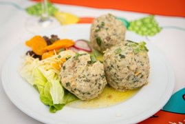 Auf dem Bild ist ein Teller mit Knödeln und buntem Gemüse zu sehen.