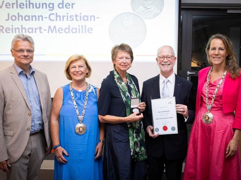 Auf dem Bild sind drei Frauen und zwei Männer zu sehen. Ein Paar hält Urkunde und Medaille in den Händen.