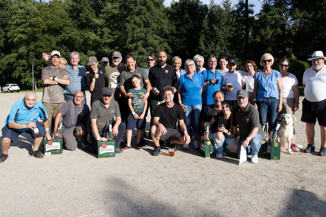 Auf dem Bild sind mehr als 20 Personen zu sehen, die an einem sonnigen Tag draußen nebeneinanderstehen und -knien.