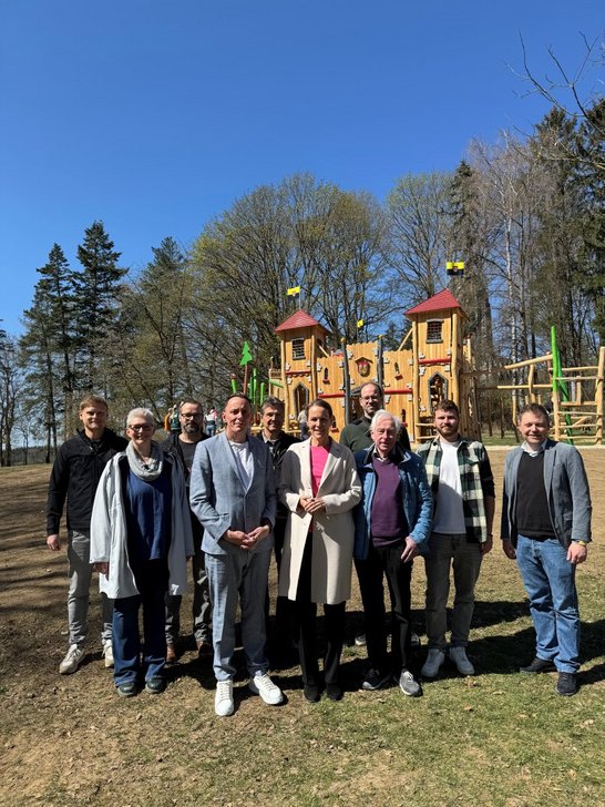 Auf dem Bild sind 10 Personen vor einer hölzernen Spielburg zu sehen.