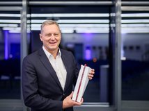 Auf dem Bild ist ein Mann zu sehen, der einen Preis in Händen hält.