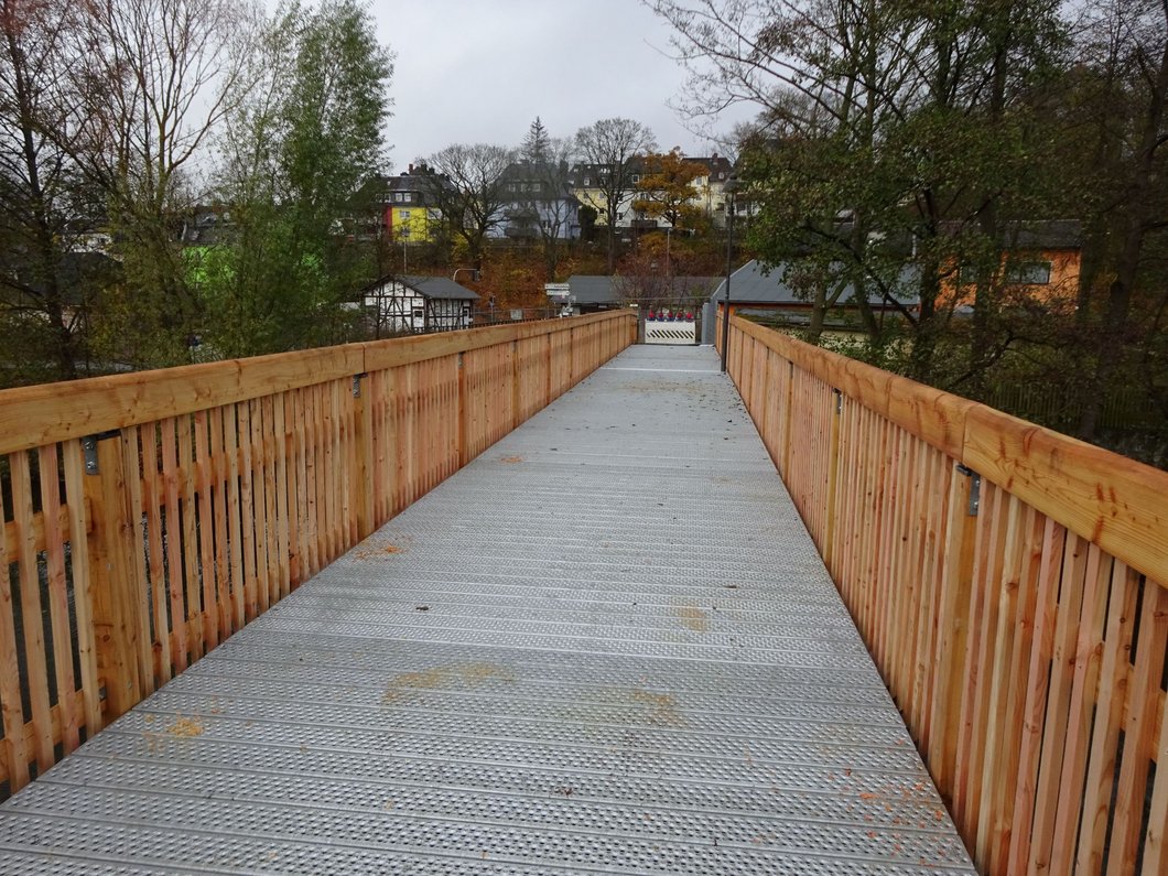Auf dem Bild ist eine Brücke mit sichtbar neuem Bodenbelag und neuem Holzgeländer zu sehen.