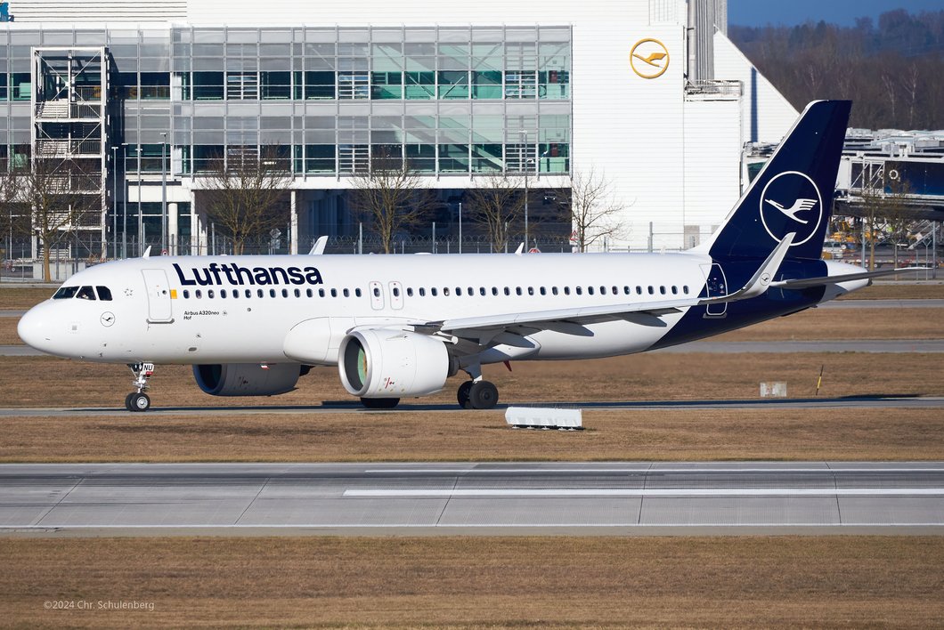 Auf dem Bild ist ein großes Lufthansa-Flugzeug zu sehen, das vor einem Terminal steht.