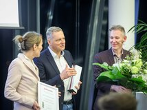 Auf dem Foto sind frei Personen zu sehen, die einen Preis, eine Urkunde und Blumen halten.