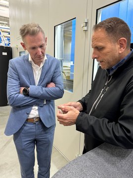 Auf dem Foto ist ein Mann zu sehen, der einem anderen Mann etwas erklärt.