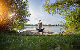Eine Frau macht Yoga am See.