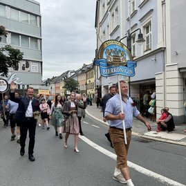 Auf dem Bild sind mehrere Mensch in Tracht zu sehen, die auf der Straße laufen.