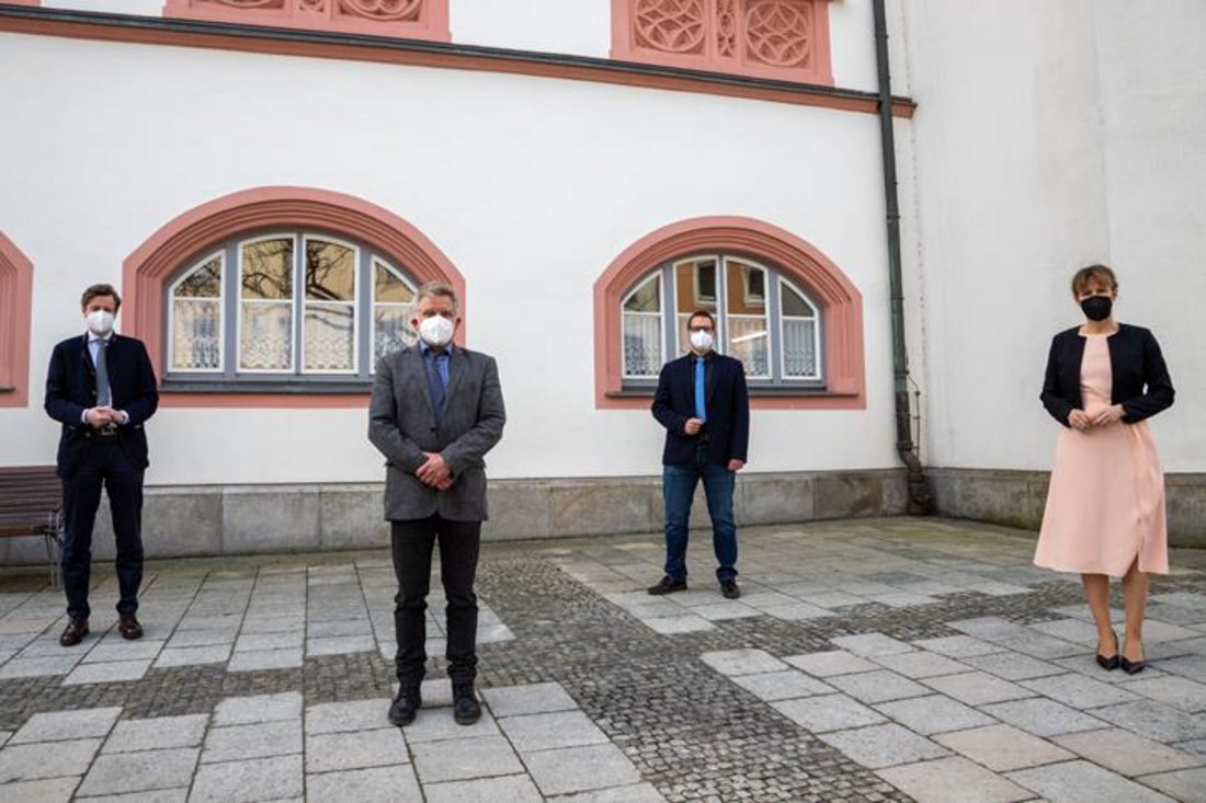 Auf diesem Foto stehen vier Menschen mit Mundschuttz und Abstand vor dem Rathaus