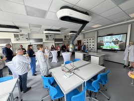 Auf dem Bild sind mehr als zehn Leute in einem Raum zu sehen, in dem viele technische Geräte stehen.