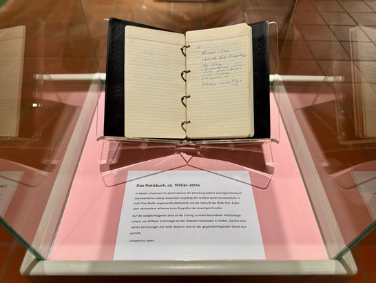 Auf dem Bild ist ein Notizbuch in einer Vitrine zu sehen.