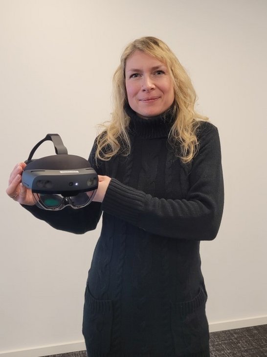 Auf dem Bild ist eine Frau zu sehen, die eine VR-Brille in den Händen hält.