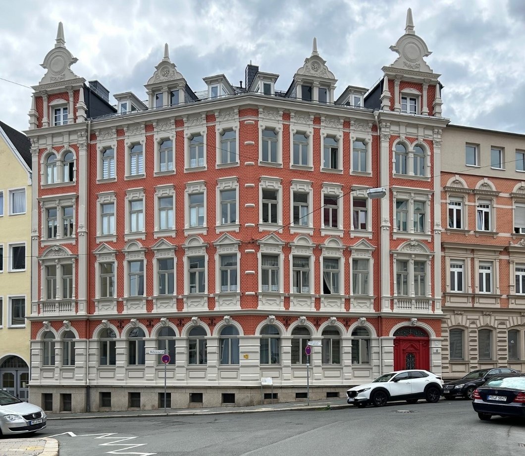 Auf dem Bild ist ein großes fünfstöckiges Stadthaus mit prächtig verzierter Backsteinfassade zu sehen.