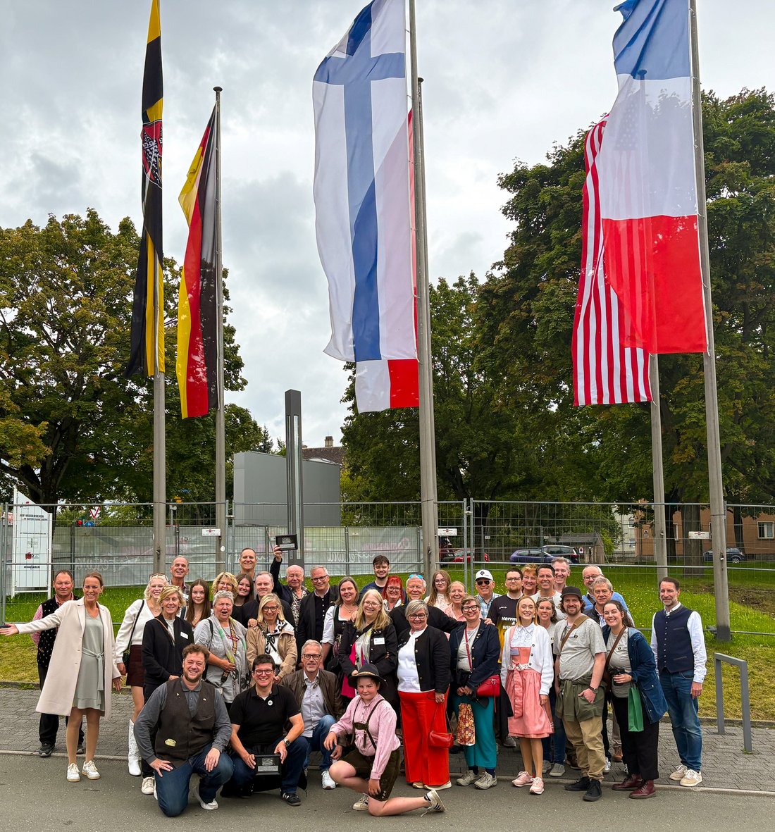 Auf dem Bild sind mehr als 30 Personen vor sechs Fahnen zu sehen.