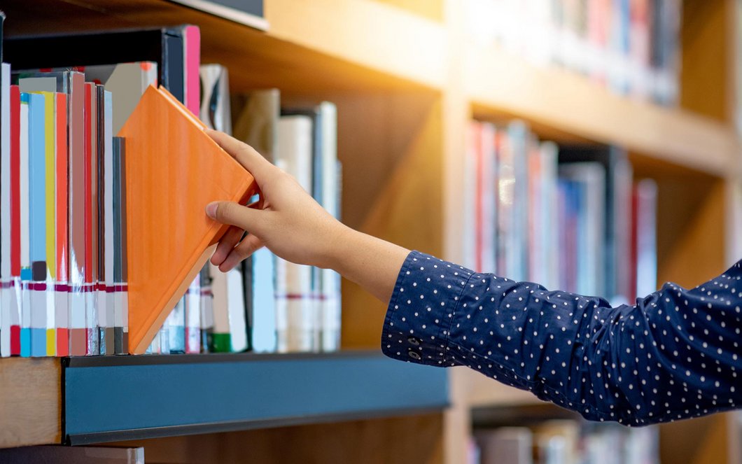 Frau nimmt ein Buch aus dem Regal