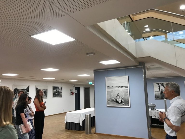 Auf dem Foto sind junge Menschen und ein Mann zu sehen, die gemeinsam eine Fotoausstellung betrachten.