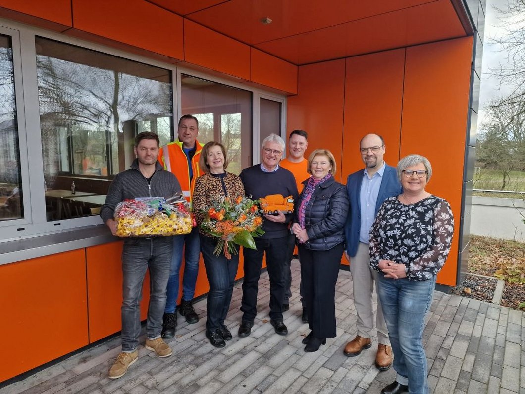 Auf dem Bild sind acht Personen vor dem Hofer Bauhof zu sehen, mit Blumen und Geschenken in Händen.