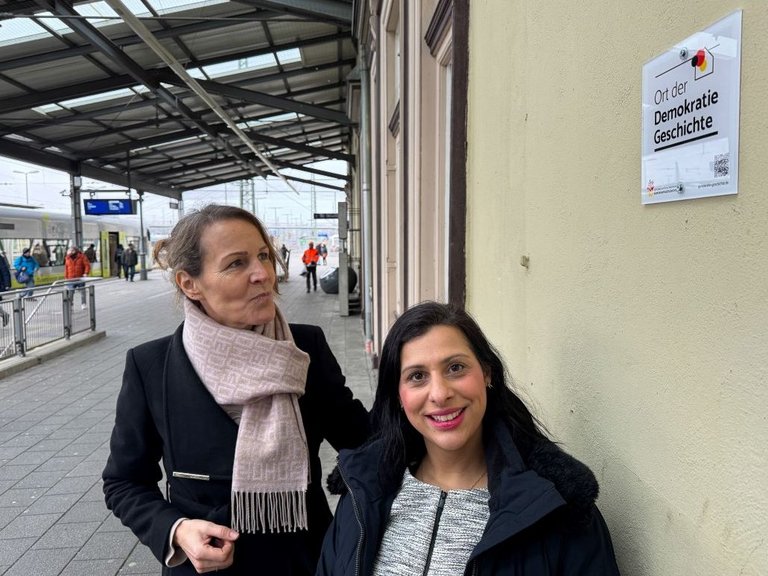 Auf dem Bilder sind zwei Frauen vor dem Bahnhofsgebäude zu sehen.