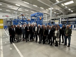 Auf dem Bild ist eine große Gruppe Personen in einer Fabrikhalle zu sehen.
