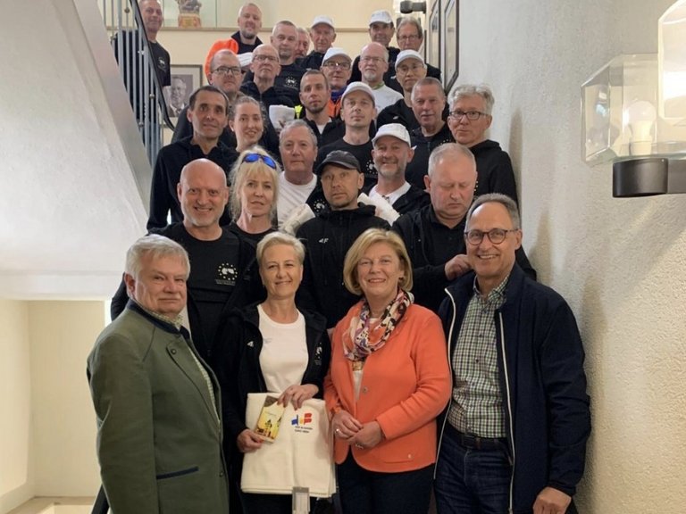 Auf dem Bild ist ein Gruppe von Menschen auf einer Treppe zu sehen, die meisten in Sportkleidung.