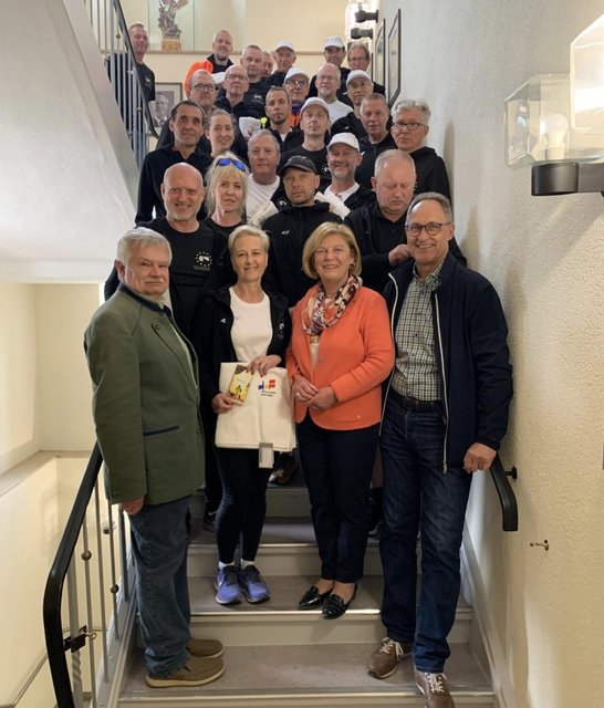 Auf dem Bild ist ein Gruppe von Menschen auf einer Treppe zu sehen, die meisten in Sportkleidung.