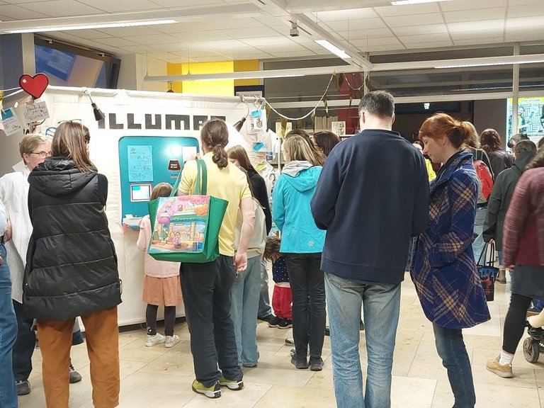 Auf dem Bild sind circa 20 Menschen zu sehen, jung und alt, die im Foyer der Stadtbücherei stehen.
