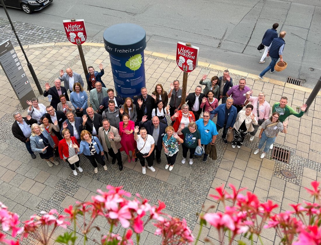 Auf dem Bild sind ca. 40 Personen zu sehen, die vor Volksfest-Schildern stehen und winken.