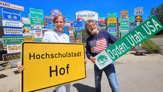 Auf dem Bild sind eine Frau und ein Mann zu sehen, die Schilder hochhalten.