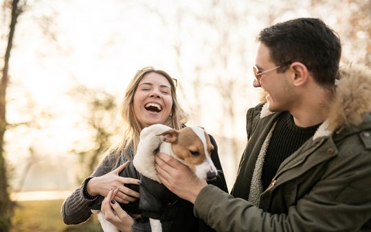 Auf diesem Foto ist ein lachendes Paar mit Hund zu sehen