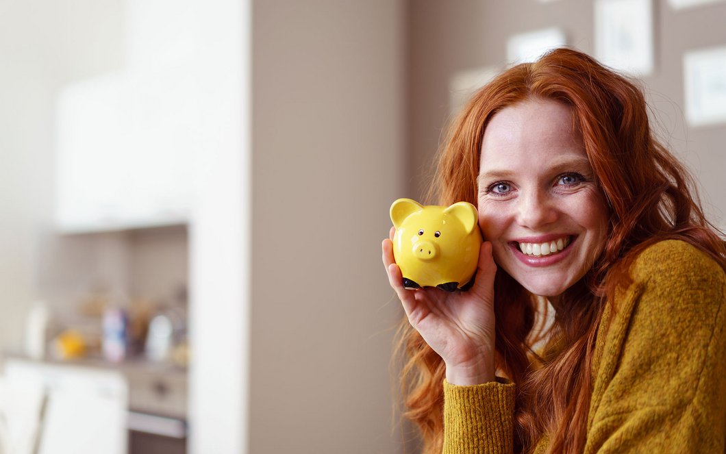 Auf diesem Foto ist eine Frau mit Sparschwein zu sehen