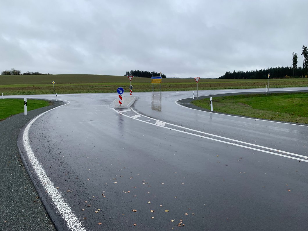Auf dem Bild ist eine frisch ausgebaute Straßeneinmündung zu sehen.