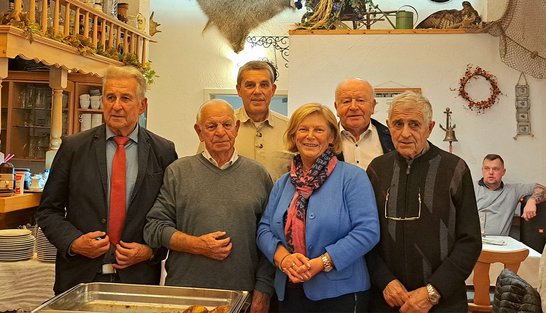 Auf dem Bild sind fünf Männer und eine Frau in einer Gaststätte zu sehen.