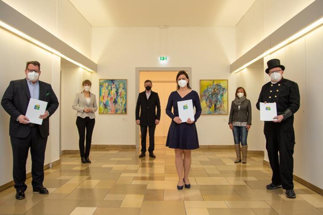 Gruppenfoto mit Eva Döhla mit Urkunde für Umwelt- und Klimapakt in den Händen