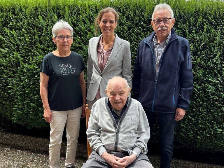 Auf dem Bild sieht man zwei Damen und zwei Herren vor einer Hecke stehen.