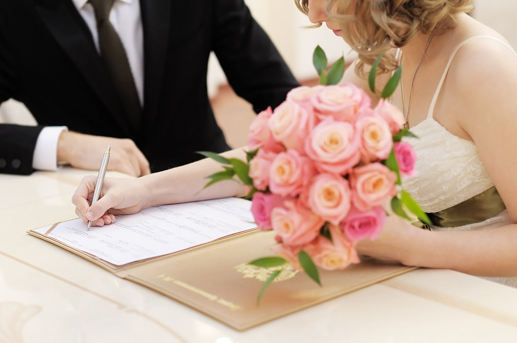 Foto des Brautpaares beim Unterschreiben mit Blumenstrauß