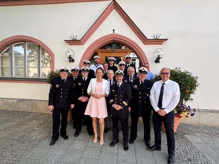 Auf dem Bild ist eine Gruppe von Marinesoldaten mit einer zivil gekleideten Frau vor dem Hofer Rathaus zu sehen.