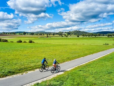Auf dem Bild sieht man einen Radweg im Grünen