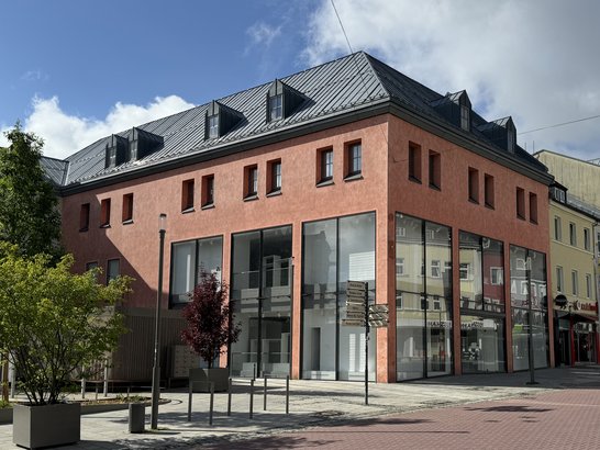 Auf diesem Bild ist ein mehrgeschossiges Gebäude mit großen Schaufenstern zu sehen.