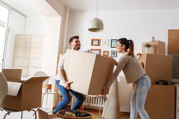 Couple carries moving boxes