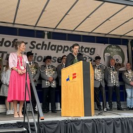 Ein Mann in historischem Kostüm steht auf einer Bühne am Rednerpult und liest vor.